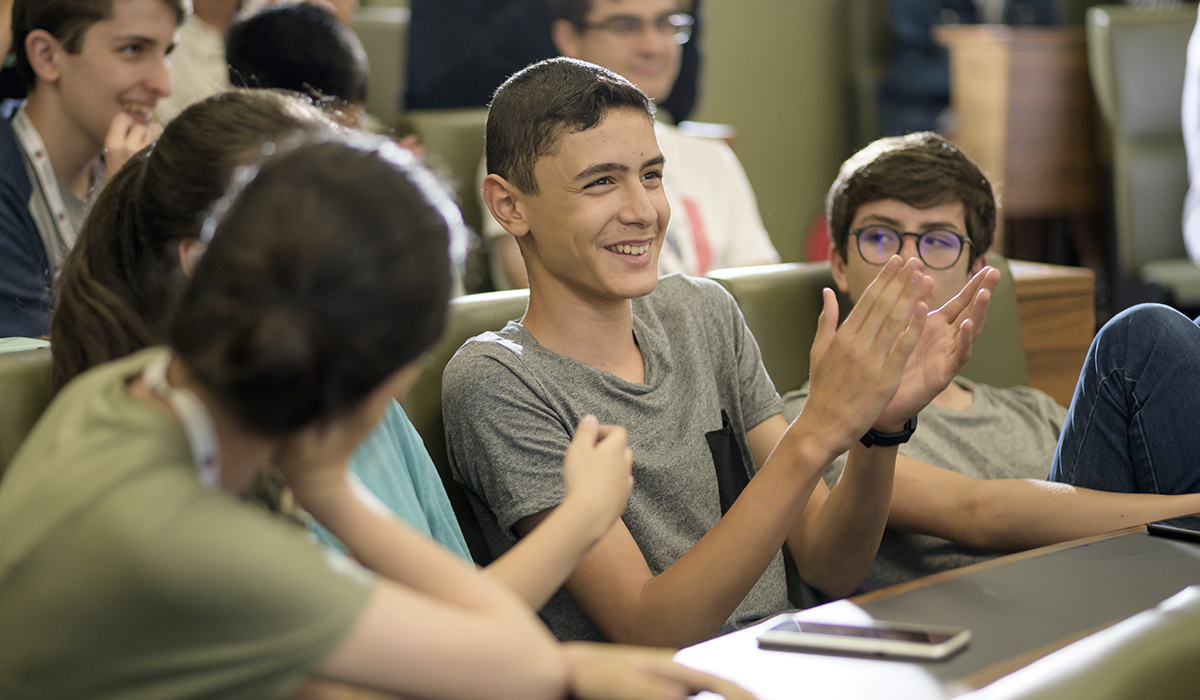 A student smiles and applauds while sitting in the lecture theatre.