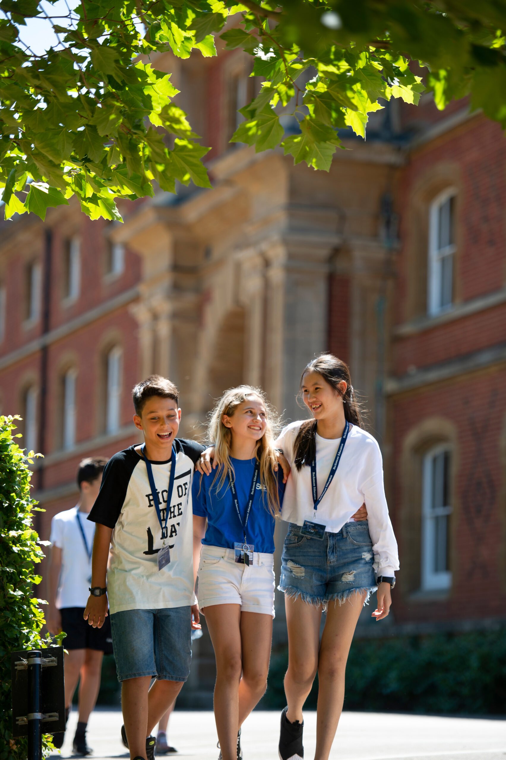 Three Bucksmore students walking together in sunny location, smiling and laughing during their summer camp